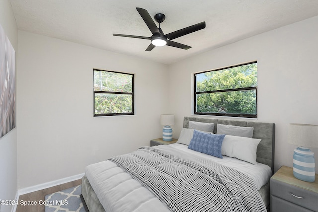 bedroom with ceiling fan, wood-type flooring, and a textured ceiling