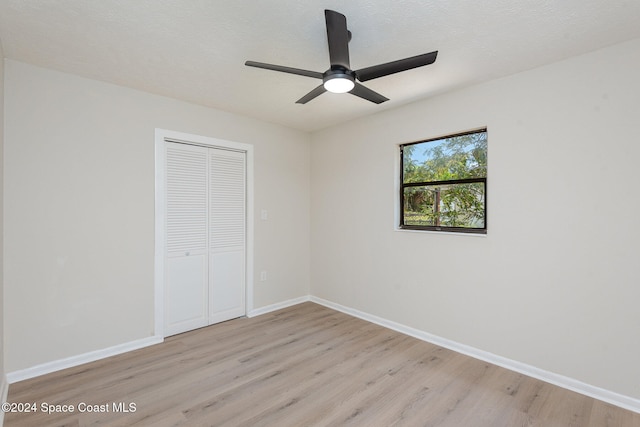 unfurnished bedroom featuring a textured ceiling, a closet, light hardwood / wood-style floors, and ceiling fan