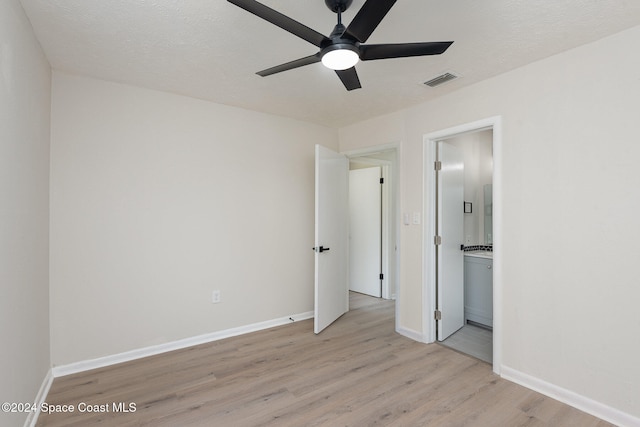 unfurnished bedroom with a textured ceiling, ceiling fan, light wood-type flooring, and ensuite bathroom