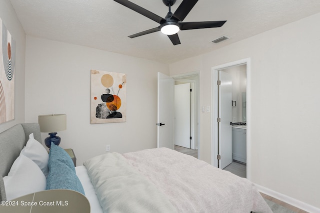 bedroom with ceiling fan, a textured ceiling, connected bathroom, and light hardwood / wood-style flooring