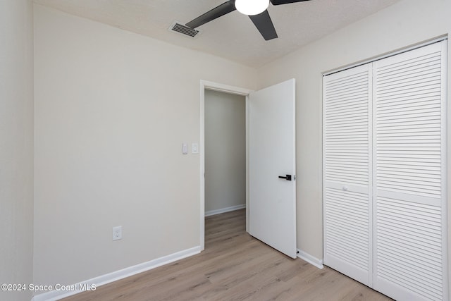 unfurnished bedroom with a textured ceiling, ceiling fan, light hardwood / wood-style flooring, and a closet