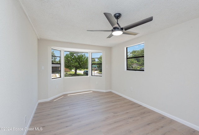 empty room with a wealth of natural light, ceiling fan, and light hardwood / wood-style floors