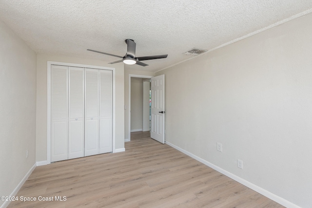 unfurnished bedroom featuring ceiling fan, a closet, a textured ceiling, and light hardwood / wood-style flooring