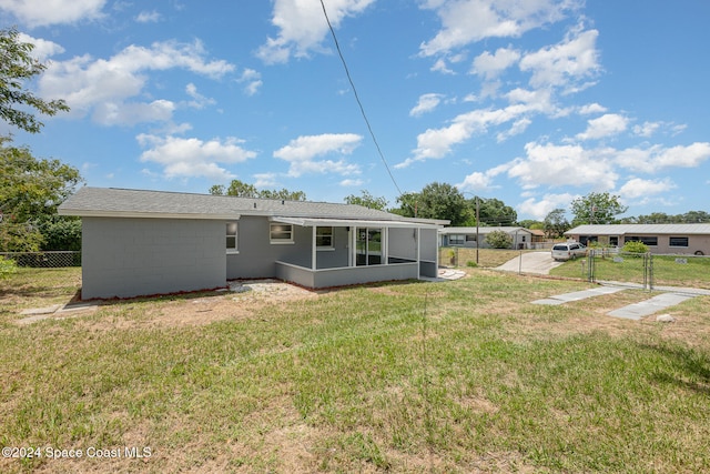 rear view of property featuring a sunroom and a lawn