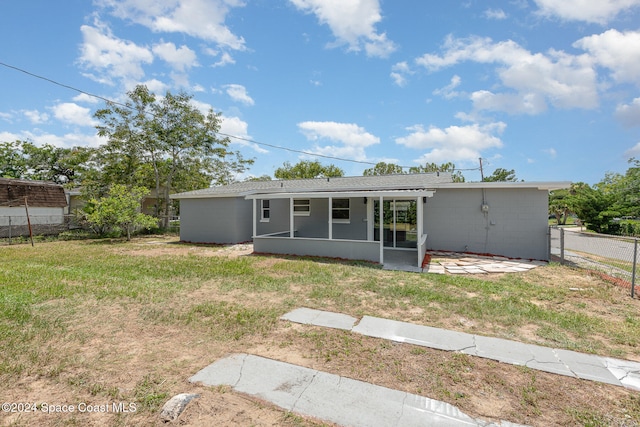 rear view of house with a yard and a sunroom