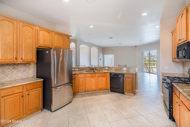 kitchen with black appliances, sink, light stone countertops, light tile patterned floors, and kitchen peninsula