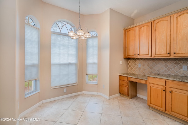 kitchen with decorative backsplash, light stone countertops, hanging light fixtures, and a healthy amount of sunlight