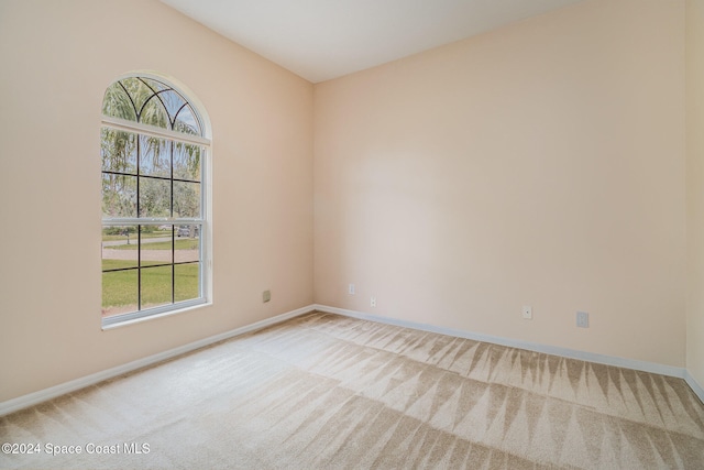 spare room with light colored carpet, plenty of natural light, and lofted ceiling