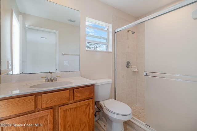 bathroom with vanity, toilet, and a shower with door