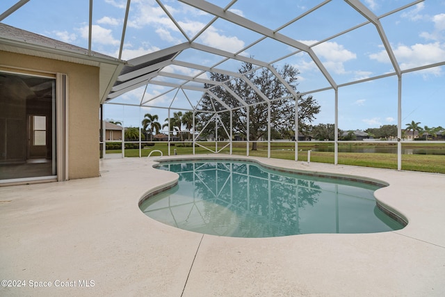 view of pool featuring a lawn, glass enclosure, and a patio