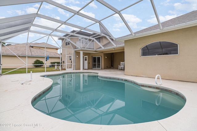 view of pool with glass enclosure and a patio area