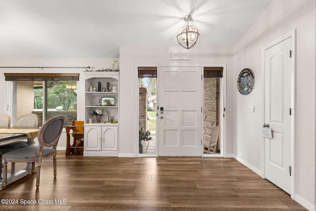 foyer featuring plenty of natural light, dark wood-type flooring, and a notable chandelier