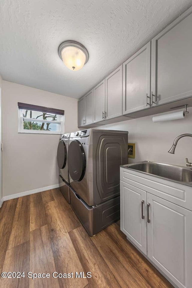 washroom featuring cabinets, a textured ceiling, dark wood-type flooring, sink, and washer and dryer