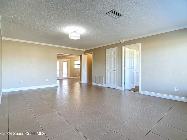 tiled empty room featuring crown molding and a textured ceiling