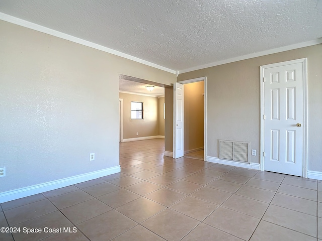 tiled spare room featuring a textured ceiling and ornamental molding