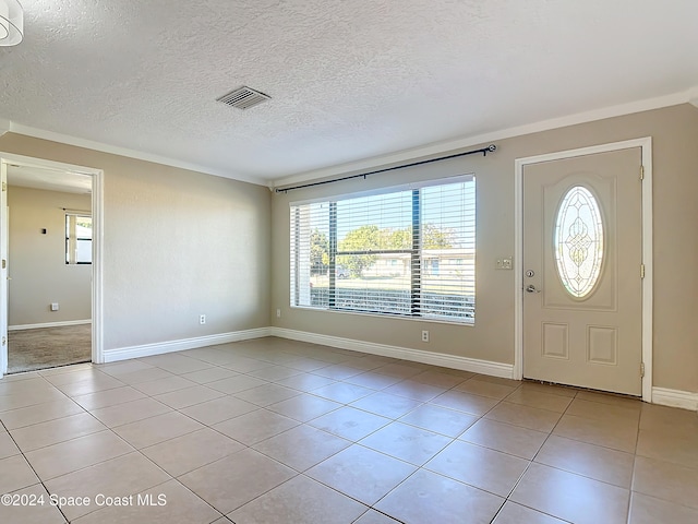 entrance foyer featuring crown molding, light tile patterned floors, a healthy amount of sunlight, and a textured ceiling