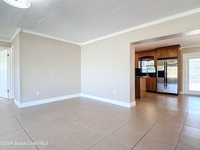 tiled spare room with sink, ornamental molding, and a textured ceiling