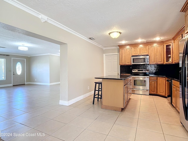 1037 Poinsetta St, Cocoa, FL 32927 - kitchen featuring appliances with stainless steel finishes, a textured ceiling, light tile patterned floors, dark countertops, and a kitchen breakfast bar