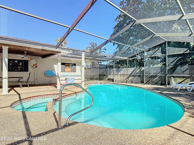 view of swimming pool featuring a patio, glass enclosure, and ceiling fan