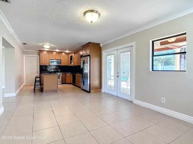 kitchen featuring a center island, french doors, crown molding, a kitchen bar, and appliances with stainless steel finishes