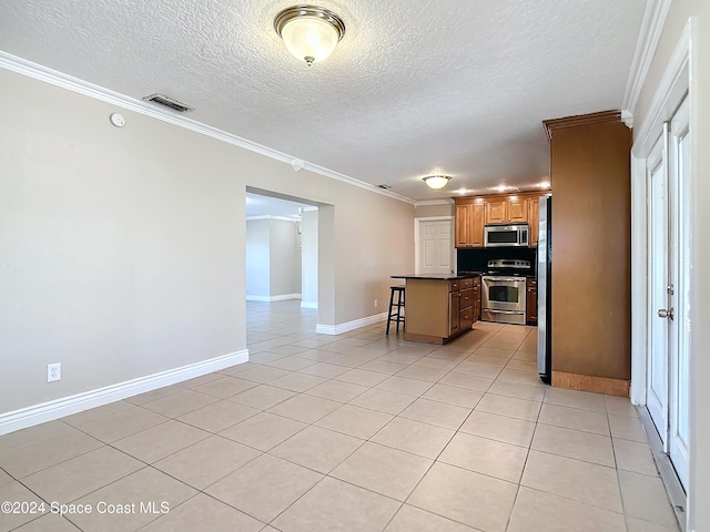 kitchen featuring crown molding, light tile patterned floors, a kitchen island, a kitchen bar, and stainless steel appliances