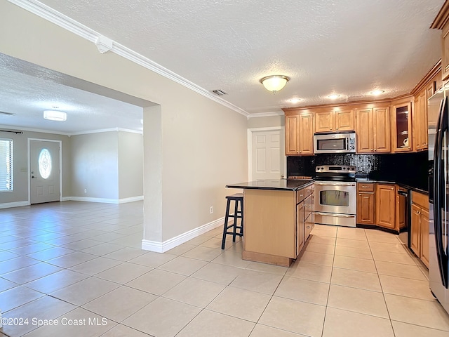 kitchen featuring appliances with stainless steel finishes, a kitchen breakfast bar, crown molding, light tile patterned floors, and a center island