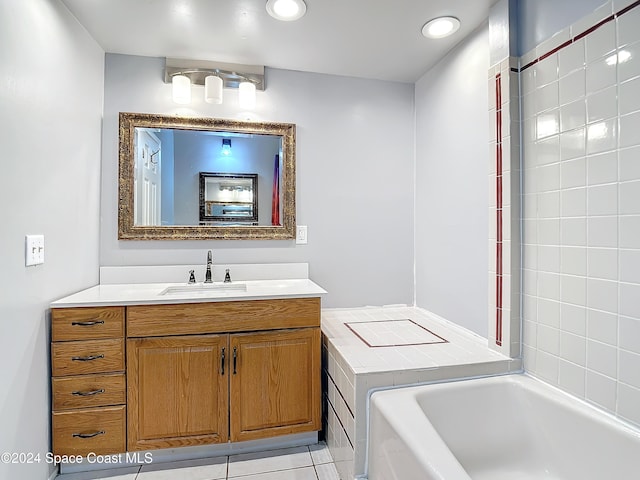 bathroom with tile patterned floors, vanity, and a relaxing tiled tub