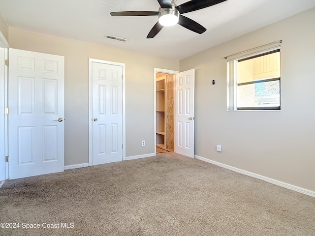 unfurnished bedroom with ceiling fan, light colored carpet, and a spacious closet