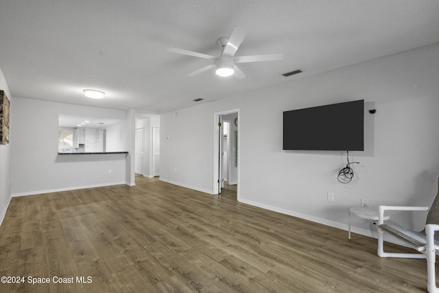 unfurnished living room with ceiling fan, wood-type flooring, and a textured ceiling