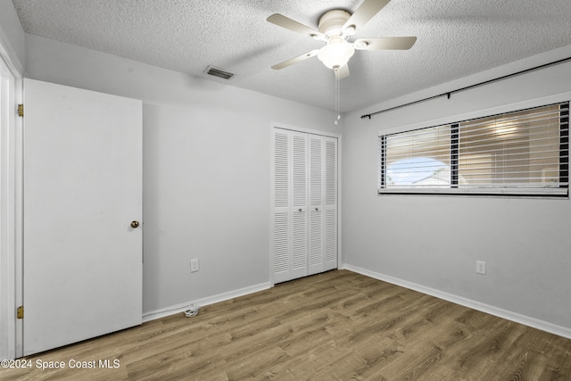 unfurnished bedroom with ceiling fan, a closet, a textured ceiling, and hardwood / wood-style flooring