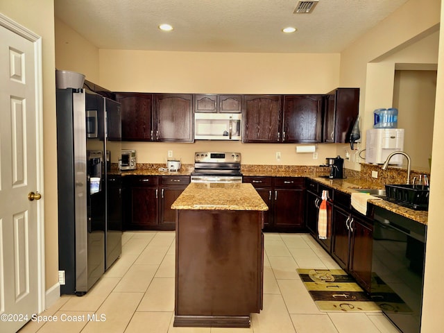 kitchen featuring light stone countertops, sink, light tile patterned floors, a kitchen island, and black appliances