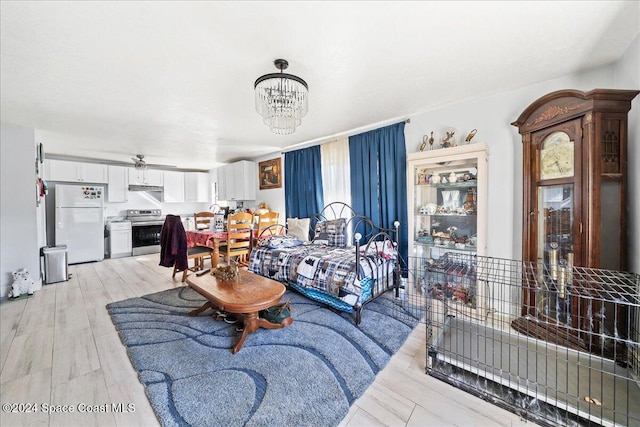 living room with ceiling fan with notable chandelier and light hardwood / wood-style floors