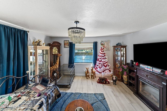 bedroom featuring a textured ceiling, light hardwood / wood-style floors, and a notable chandelier