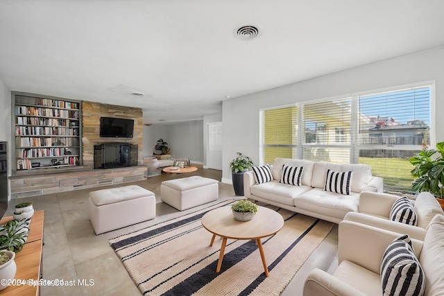 tiled living area with built in shelves, visible vents, and a stone fireplace