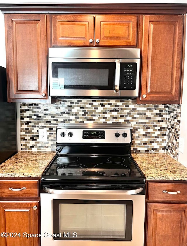 kitchen featuring decorative backsplash, light stone counters, and appliances with stainless steel finishes