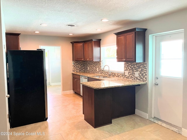 kitchen with kitchen peninsula, backsplash, black fridge, stainless steel dishwasher, and sink