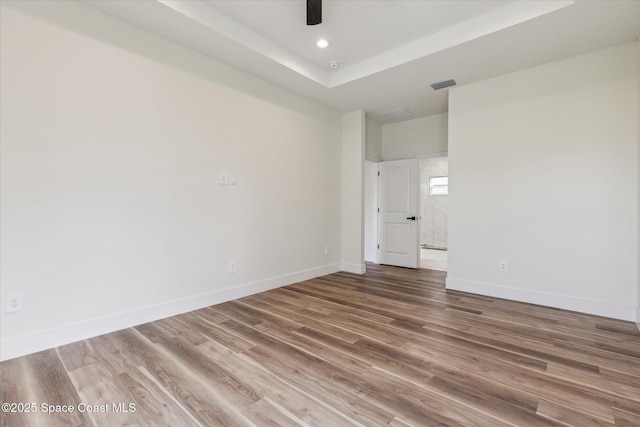 unfurnished room with ceiling fan, wood-type flooring, and a tray ceiling