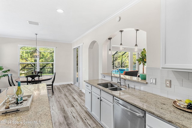 kitchen featuring stainless steel dishwasher, a healthy amount of sunlight, light stone counters, and sink