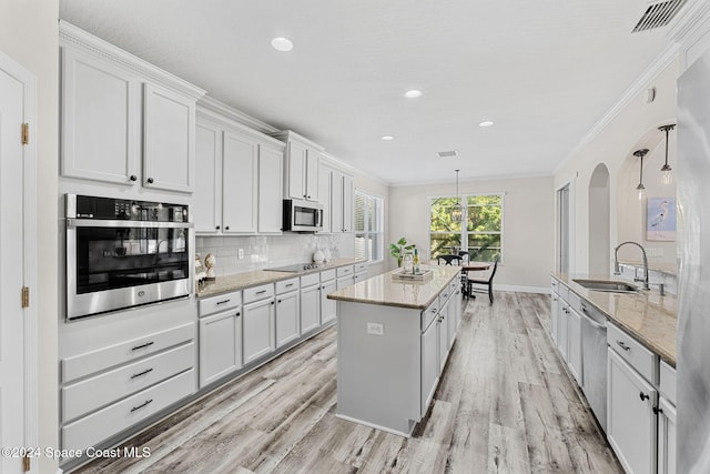 kitchen with white cabinets, sink, hanging light fixtures, light hardwood / wood-style flooring, and stainless steel appliances