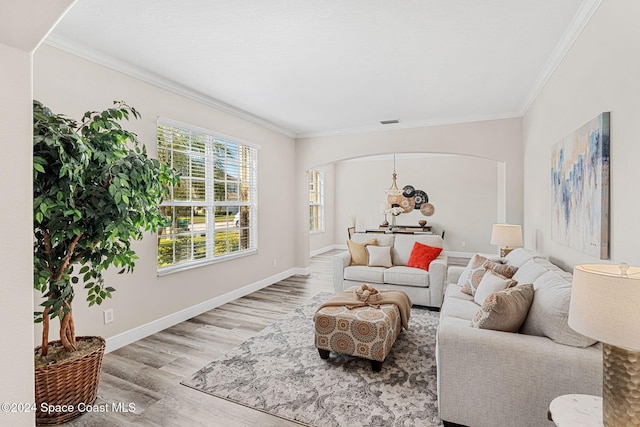 living room with a notable chandelier, ornamental molding, and light hardwood / wood-style flooring