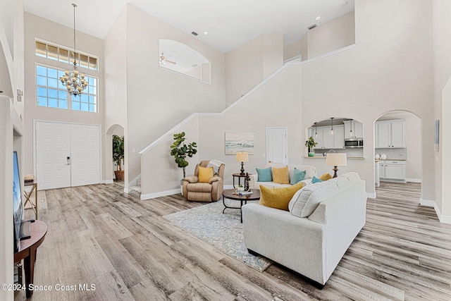 living room featuring a notable chandelier, a towering ceiling, and light hardwood / wood-style flooring