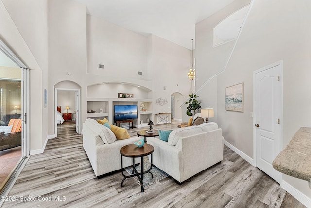 living room with hardwood / wood-style floors, built in shelves, and a towering ceiling