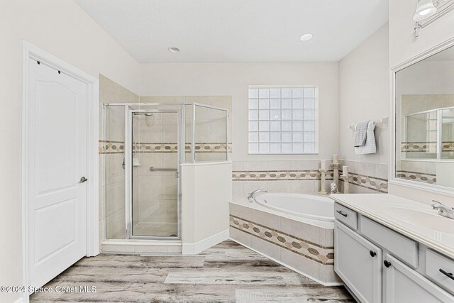 bathroom featuring hardwood / wood-style flooring, vanity, and separate shower and tub