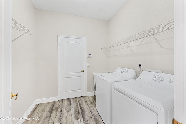 laundry room featuring light hardwood / wood-style flooring, a textured ceiling, and independent washer and dryer