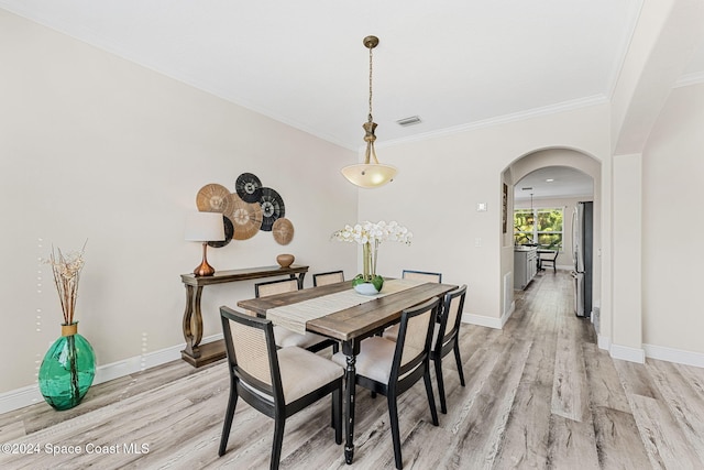 dining area with ornamental molding and light wood-type flooring