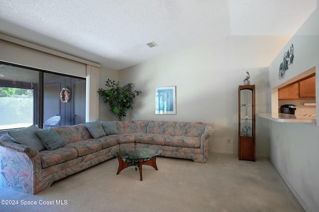 living room with light colored carpet, a textured ceiling, and vaulted ceiling