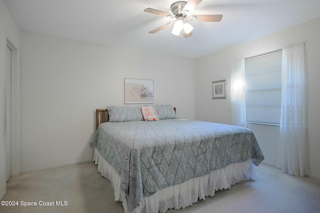 bedroom with a textured ceiling, ceiling fan, and light carpet