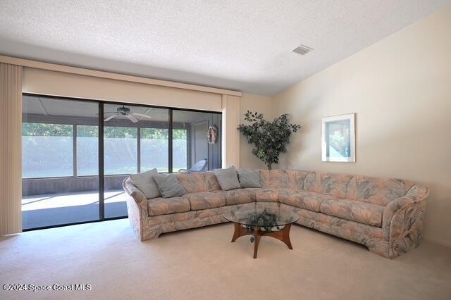 carpeted living room with ceiling fan and a textured ceiling