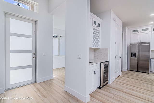 kitchen with wine cooler, white cabinetry, light hardwood / wood-style flooring, and stainless steel refrigerator with ice dispenser