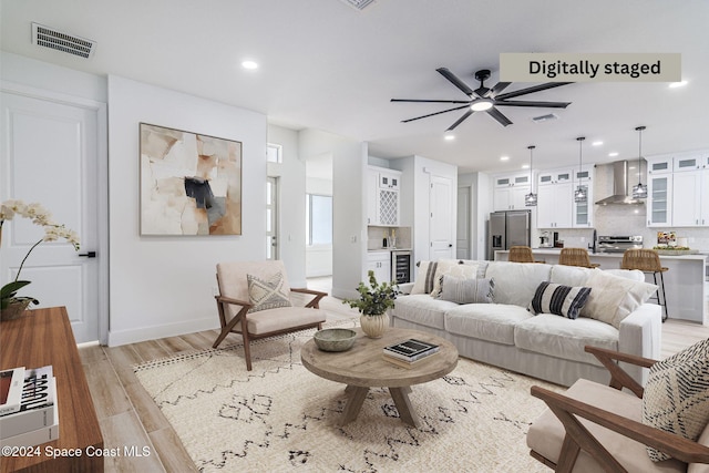 living room with ceiling fan, wine cooler, and light hardwood / wood-style flooring